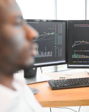 African-American broker works in office using workstation and analysis technology.